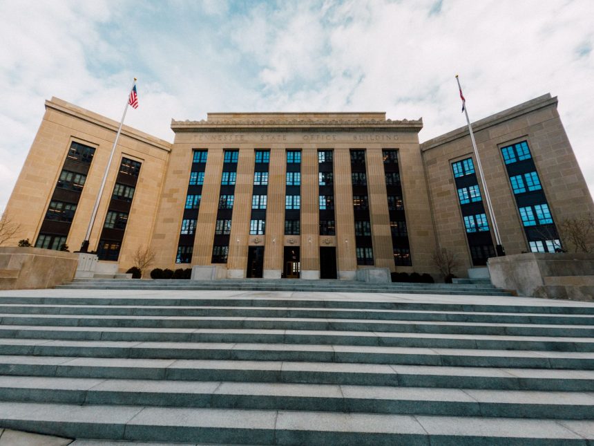 Exterior do prédio do Federal Reserve, visto de baixo, com bandeiras dos Estados Unidos e escadaria.