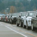 Fileira de SUVs novos estacionados em um pátio externo de concessionária.