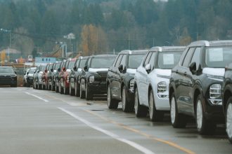 Fileira de SUVs novos estacionados em um pátio externo de concessionária.