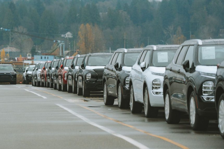 Fileira de SUVs novos estacionados em um pátio externo de concessionária.