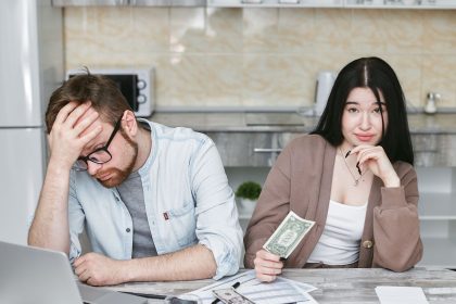 Casal analisa as finanças e organiza o orçamento sobre a bancada de uma cozinha.