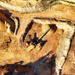Vista aérea de uma extensa mina a céu aberto, com máquinas pesadas escavando o terreno.
