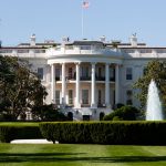 Fachada sul da Casa Branca, em Washington, com fonte e jardim em um dia ensolarado.