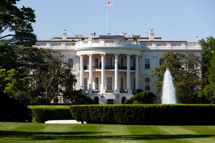 Fachada sul da Casa Branca, em Washington, com fonte e jardim em um dia ensolarado.