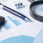 Calculadora, caneta e lupa sobre documentos financeiros, simbolizando a análise detalhada de riscos de crédito.