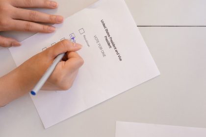 Mão depositando uma cédula em uma urna durante um processo eleitoral.