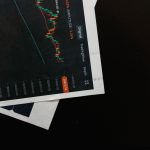 Close de um gráfico financeiro com dados de mercado sobre uma superfície preta.