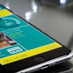 Smartphone exibindo a interface de um aplicativo de cobrança sobre uma superfície reflexiva.