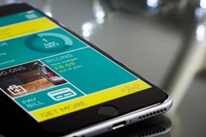 Smartphone exibindo a interface de um aplicativo de cobrança sobre uma superfície reflexiva.