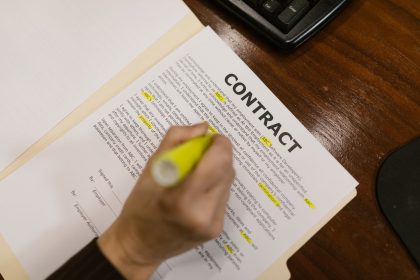Pessoa destacando trechos de um contrato financeiro sobre uma mesa de escritório.