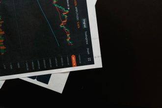 Close de um gráfico financeiro com dados de mercado sobre uma superfície preta.
