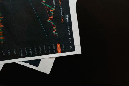 Close de um gráfico financeiro com dados de mercado sobre uma superfície preta.