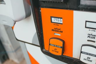 Detalhe de uma bomba de gasolina exibindo preço e nível de octanagem 87.